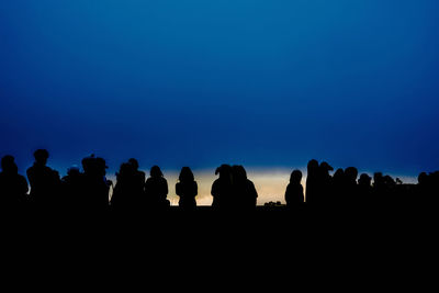 Silhouette people standing against clear blue sky at night
