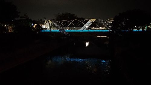 Illuminated bridge over river in city at night