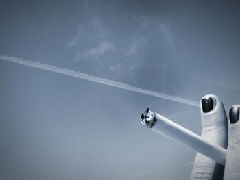 Low angle view of cropped hand against blue sky