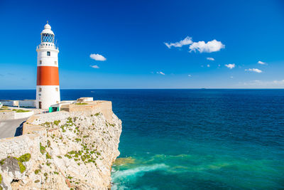 Lighthouse by sea against sky