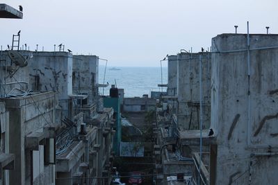 Buildings by sea against clear sky