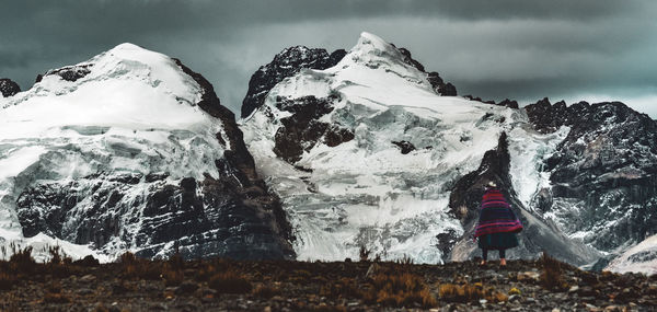 Rear view of woman standing against snowcapped mountains