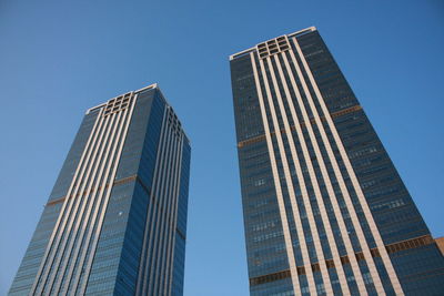 Low angle view of modern buildings against clear blue sky