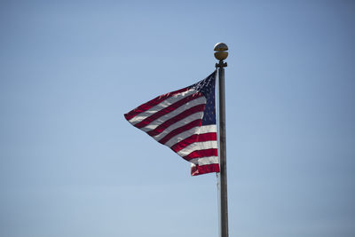 Low angle view of flags against clear blue sky