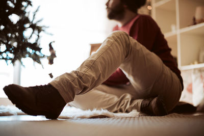 Midsection of man sitting on bed at home