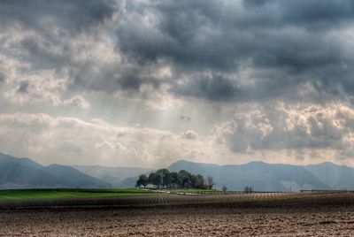 Scenic view of field against cloudy sky