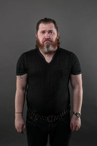 Portrait of mature man standing against black background