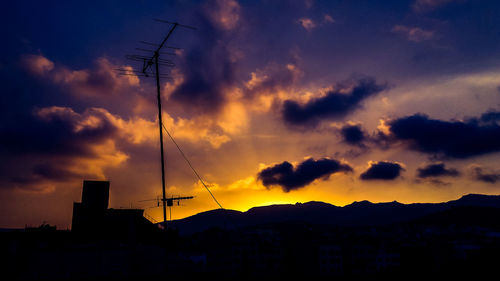 Low angle view of silhouette communications tower against sky during sunset