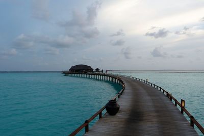 Pier on sea against cloudy sky