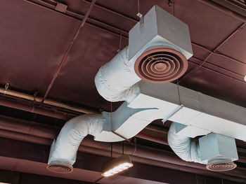 Low angle view of cooling air duct and grille under brown ceiling