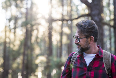 Side view of young man looking away in forest