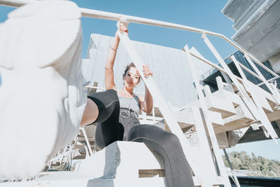 Rear view of woman sitting on railing