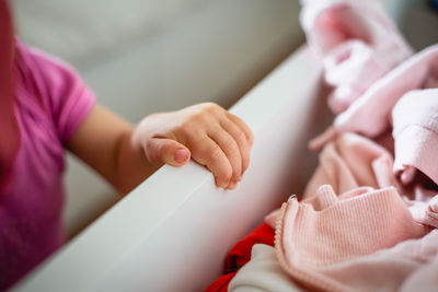 Close up view of baby hand holding the drawer full of clothes, playing alone