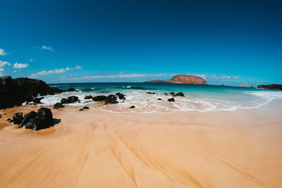 Scenic view of beach against blue sky