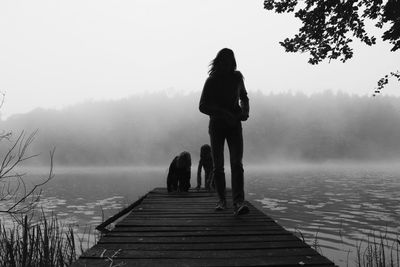 Siblings on jetty in lake during foggy weather