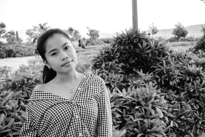 Portrait of young woman standing against plants