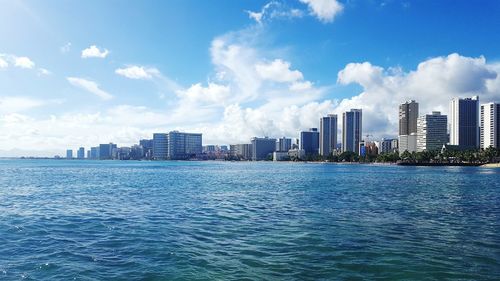 Sea by cityscape against sky