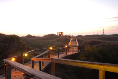 Bridge over river against sky at sunset