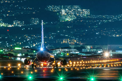 Airplane landing on illuminated airport at night