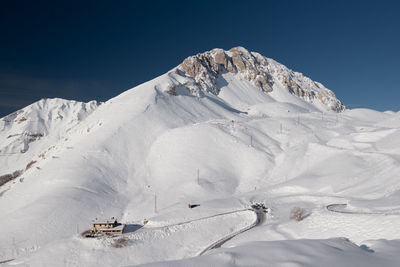 Scenic view of snow covered mountain against blue sky