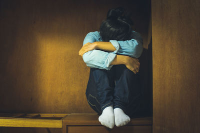 Rear view of woman standing against wall at home