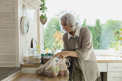 Senior woman unpacking fresh groceries in kitchen