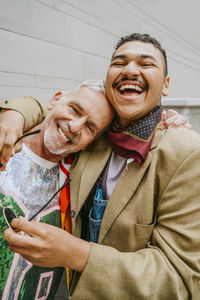 Happy mature man leaning on gay friend's shoulder