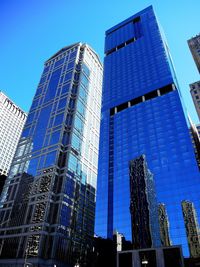 Low angle view of skyscrapers against blue sky