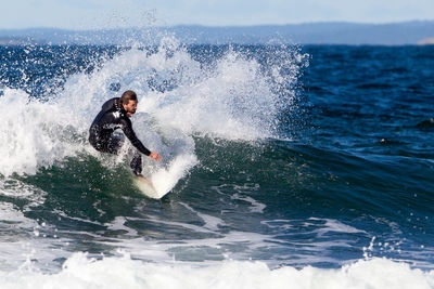 Man surfing in sea against sky