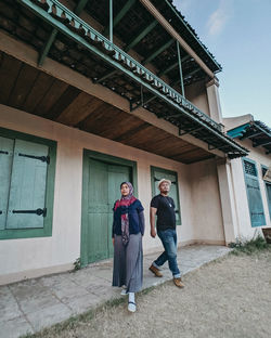 Full length portrait of friends standing against building