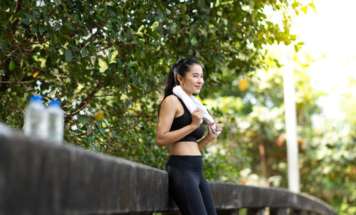 Side view of woman standing by tree against plants