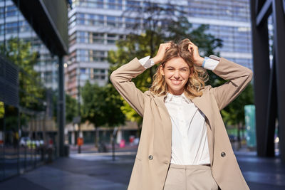 Portrait of young woman standing in city