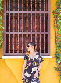 Side view of young woman standing against wall