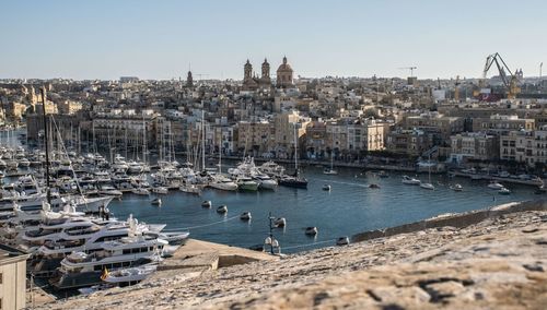 Sailboats in sea by city against clear sky