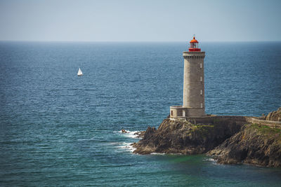 Lighthouse by sea against sky