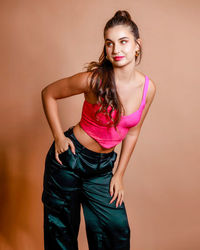Portrait of young woman standing against yellow background