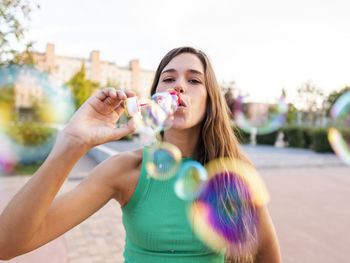 Woman blowing colorful bubbles at footpath