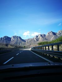 Highway seen through car windshield against blue sky