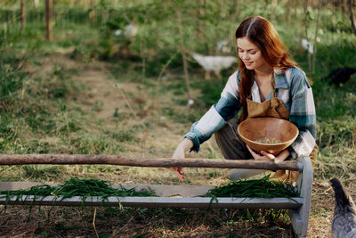 Smiling woman feeding chickens in farm