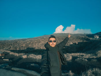 Portrait of man with sunglasses standing on mountain against sky