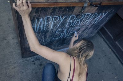 Rear view of woman with arms raised against wall