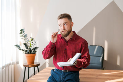 Businessman writing notes while sitting at his desk. young bearded man