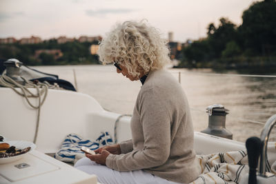 Man sitting on boat in lake against sky