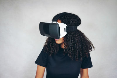 Woman wearing virtual reality simulator against wall