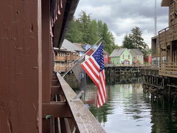 Flag on river amidst buildings against sky