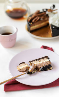 Delicious three chocolates cake slice on plate with tea on white background