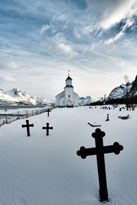 Low angle view of cross on building against sky during winter