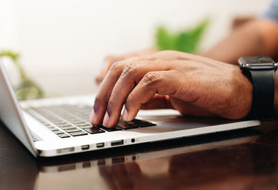 African american man at home using laptop computer to shop online with credit card in hand