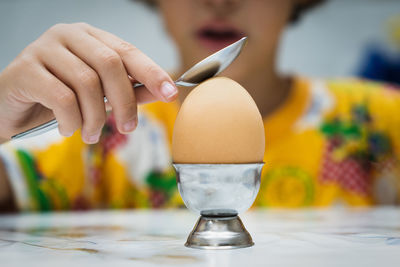 Close-up of boy with egg on table