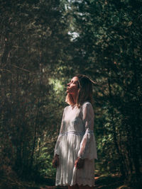 Woman standing against trees in forest